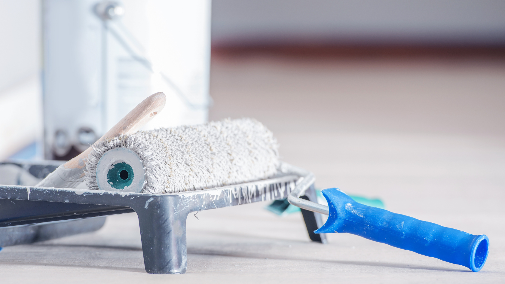 A close up of a brush and a roller on a floor