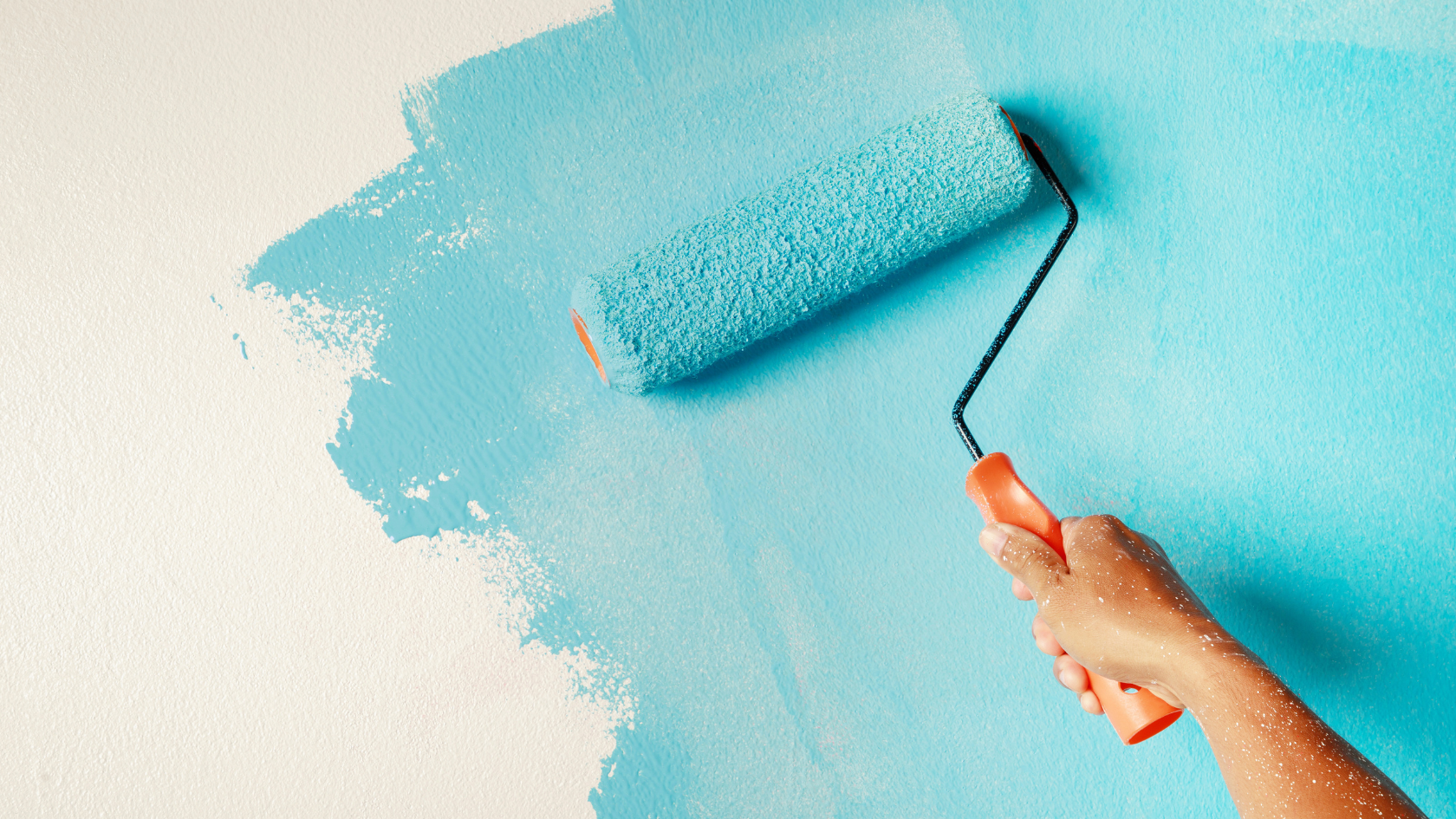 A person using a paint roller to paint a wall